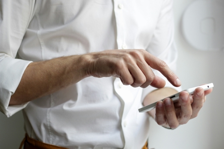 man in white shirt typing on phone