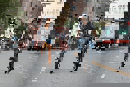 man and woman riding ebike on road with helmets